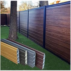 the side of a fence with different colored sidings next to trees and artificial grass