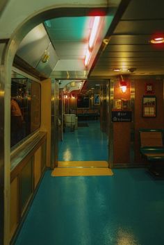 the inside of a subway car with blue flooring and yellow walls, lights on