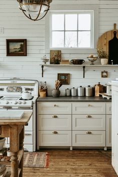 an old fashioned kitchen with white painted walls and wood flooring is pictured in this image