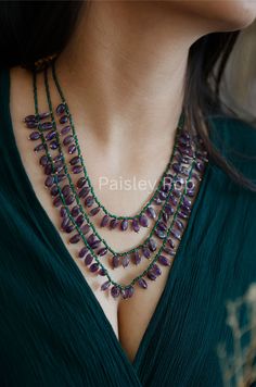 The handcrafted purple amethyst stone necklace strewn to green stones is flawlessly designed by the artisans of India to celebrate beauty with the heritage of rich old Indian Jewelry. The multi-layered necklace is designed on 22K gold plating to give you a breezy color therapy. Pair this multi-strand long necklace with your ethnic or contemporary ensembles, which can be a perfect match for any celebration. Necklace Closure - Lobster Hook Style Tip - This design is a perfect intersection of bohemian and traditional, put together thoughtfully for a modern bohemian, who loves the rich details of her traditional heritage.  Handcrafted in Jammu and Kashmir Paisley Pop travels the depths of India to learn techniques and crafts from deep down in the local markets and villages. We give utmost impo Artisan Purple Gemstone Jewelry, Artisan Purple Amethyst Jewelry, Artisan Amethyst Jewelry With Stones, Artisan Jewelry With Purple Natural Stones, Artisan Purple Jewelry With Natural Stones, Handmade Green Amethyst Gemstones, Artisan Amethyst Gemstone Beads Jewelry, Bohemian Purple Jewelry With Polished Beads, Green Amethyst Jewelry With Gemstone Beads