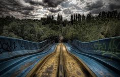 the bottom half of a skateboard ramp with graffiti on it and trees in the background