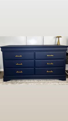 a large blue dresser with gold handles in a living room or dining room, against a white wall