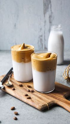 two glasses filled with coffee sitting on top of a cutting board