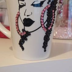 a white coffee cup with pink and black beads on it