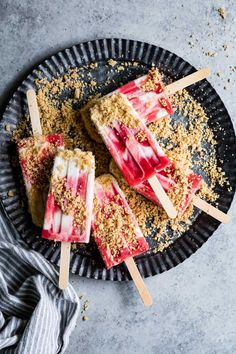 three popsicles on a plate with toppings