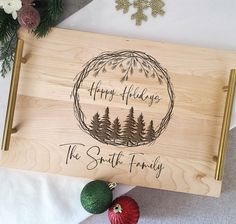 a wooden sign with the words happy holidays and pine trees on it next to ornaments