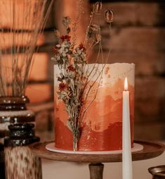 a red and white cake sitting on top of a table next to a lit candle