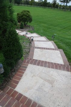 a brick walkway in the middle of a grassy field