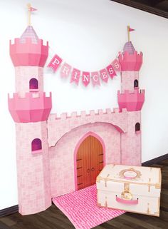 there is a pink princess castle set up on the floor next to a white suitcase