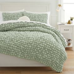 a bed with a green comforter and pillows