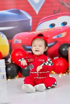 a baby boy sitting on the floor in front of balloons and cars wallpapers