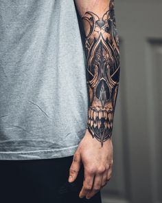 a man with a skull tattoo on his arm and hand, holding onto the wrist