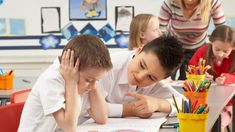 two children and an adult in a classroom