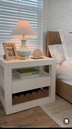 a bed with white sheets and pillows next to a lamp on top of a night stand