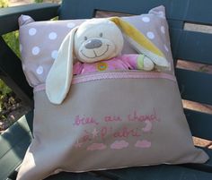 a stuffed animal sitting on top of a pink and white pillow next to a blue bench