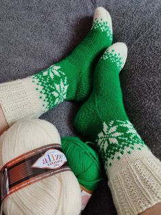 two pairs of green and white knitted socks laying next to each other on the floor