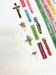 colorful stickers with cross, flowers and words on them are hanging from a white wall