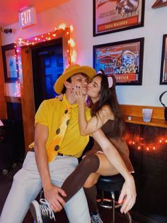 a man and woman sitting on top of a stool in front of a fire place