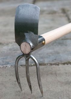 a pair of garden shears with wooden handle on concrete ground next to brick walkway