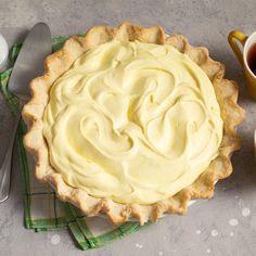 a pie sitting on top of a table next to a cup of tea and spoons