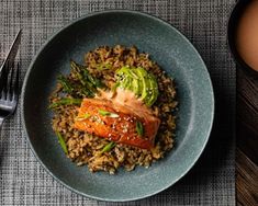 a plate with rice, salmon and asparagus next to a cup of coffee