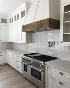 a stove top oven sitting inside of a kitchen next to white cabinets and cupboards