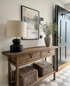 a table with two baskets underneath it and a lamp next to it on the wall