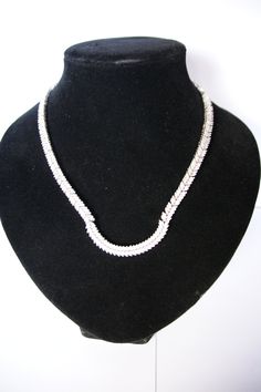 This is a fabulous Silver and Cubic Zirconia necklace. The design is absolutely stunning with alternate sections of six and four leaves encrusted with bright Cubic Zirconia stones. Each section is securely attached to the next and moves with a snake like fashion. The front section has a 'U' shape, this is rigid so holds its shape permanently. The necklace has been beautifully crafted. The catch has a safe and secure push-in catch. The necklace measures 43cm long and 0.6cm wide. It is stamped 925 Classic Cubic Zirconia Necklaces With Bling, Classic Cubic Zirconia Necklace With Bling, Classic Diamond Necklace With Bling, Elegant Cubic Zirconia Tennis Necklace With Bling, Elegant Silver Tennis Necklace With Bling, Cubic Zirconia Costume Jewelry Necklace, Elegant Cubic Zirconia Chain Necklace With Bling, Formal Fine Jewelry Necklaces With Bling, Formal Bling Fine Jewelry Necklaces