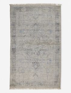 an antique rug with faded edges and fringes on the bottom, in grey tones