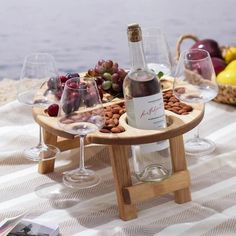 a wooden tray with wine glasses and grapes on it, next to some other items