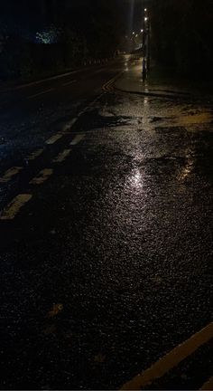 a wet street at night with the lights on and no one is in the dark