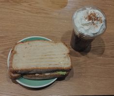 a toasted sandwich on a plate next to a cup of coffee with whipped cream