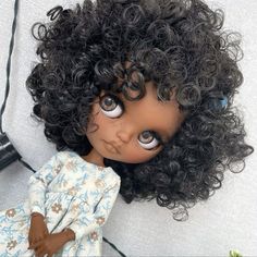 a doll with curly hair and blue eyes laying on the floor next to a wall