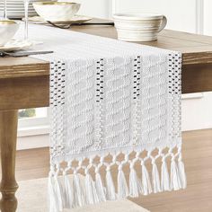 a white table runner with tassels on it