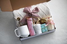 an open box with items in it on a bed next to a cup and spoon