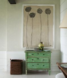 a green dresser sitting next to a painting on the wall