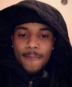 a man with piercings on his nose wearing a hoodie and looking at the camera