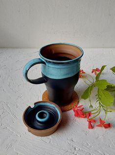 two coffee mugs sitting next to each other on a white surface with flowers in the background