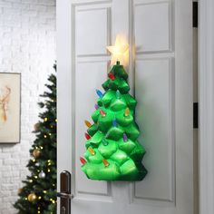 a green christmas tree shaped like a star hanging on a door with lights around it