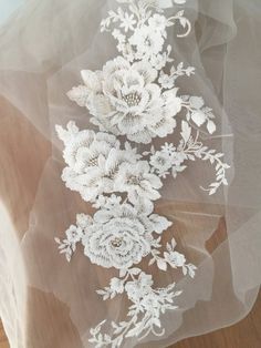 white flowers are embroidered on the sheer fabric