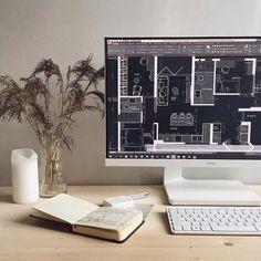 a desktop computer sitting on top of a desk next to a vase with flowers in it