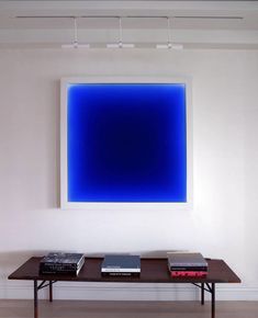 a table with two books on it in front of a large blue square wall hanging