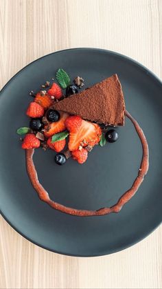 a piece of chocolate cake topped with berries and mint