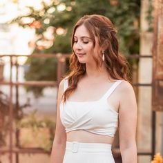 a woman wearing a white crop top and skirt