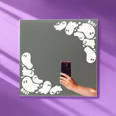 a person holding a cell phone in front of a mirror with ghost images on it