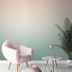 a pink chair sitting next to a table with a plant on it in front of a green wall