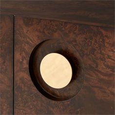 a wooden cabinet with a circular mirror on the front and side panel inlays