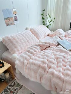 a bed covered in pink fluffy blankets and pillows