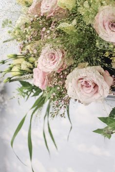 a bouquet of flowers sitting on top of a white table cloth covered tablecloth with greenery