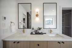 a bathroom with two sinks, mirrors and lights on the wall above them is shown